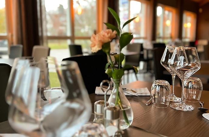 Glas och blomma på bord i matsal.